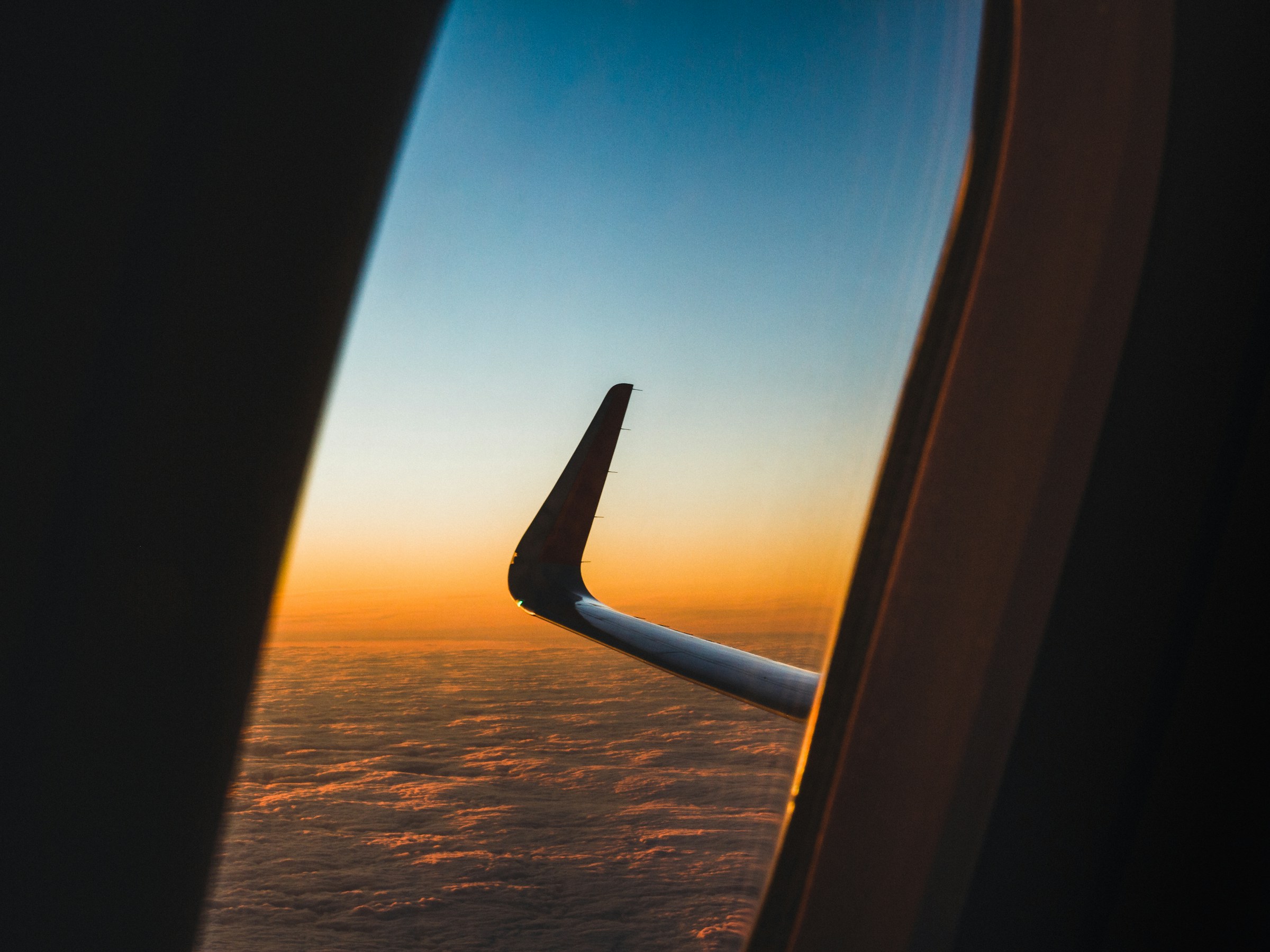 夕暮れの空を行く飛行機の翼